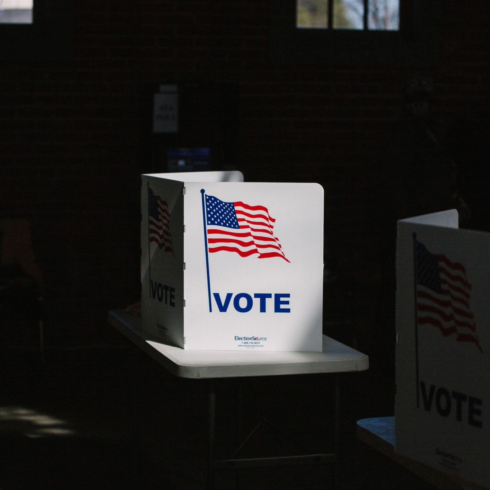 Voting privacy booth with an American flag in a darkened polling place.