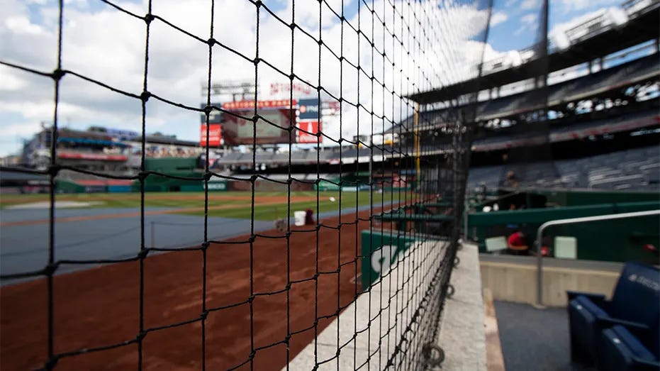 A baseball field viewed through protective netting from seats close to the action.